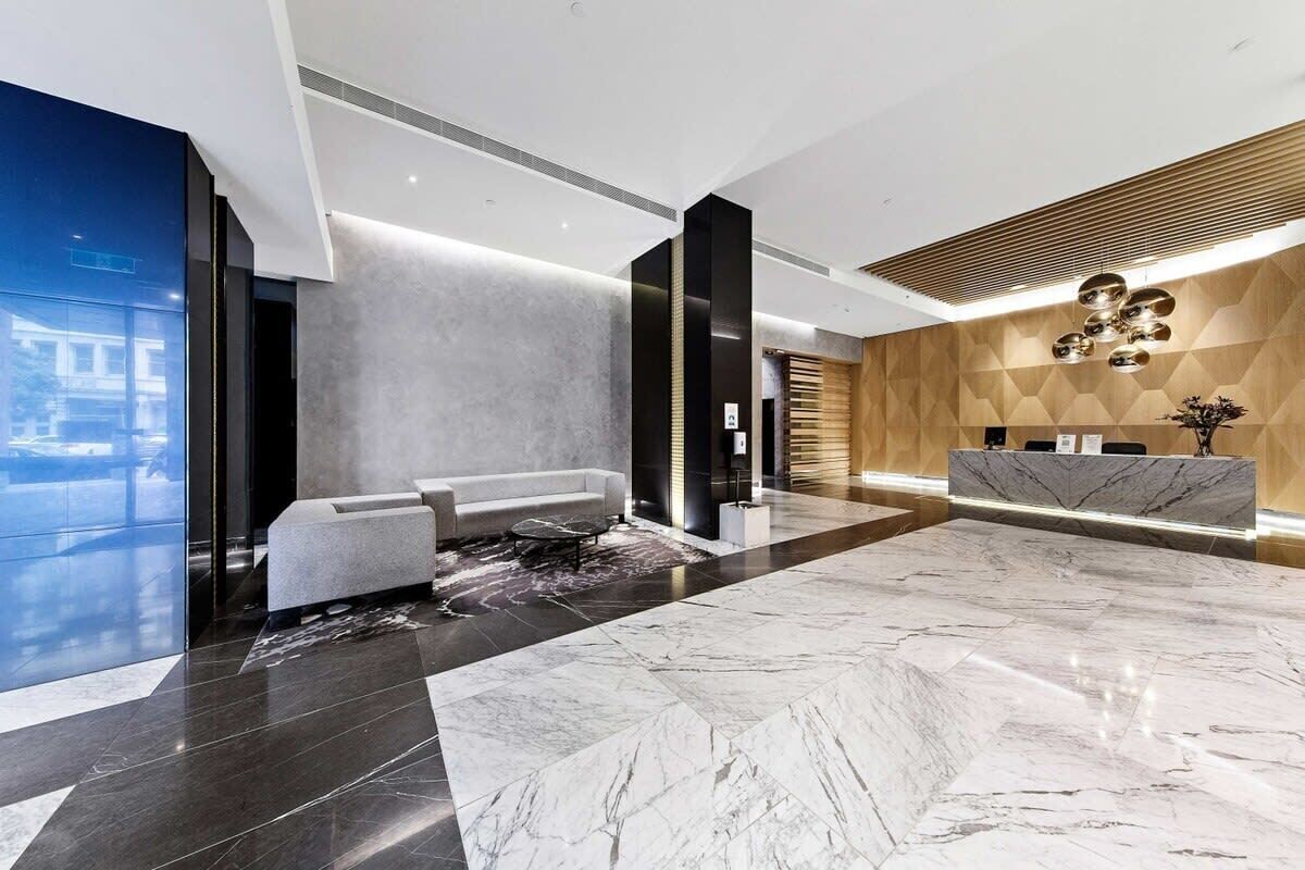 Um lobby moderno com balcão de recepção, área de estar e um amplo piso de mármore.