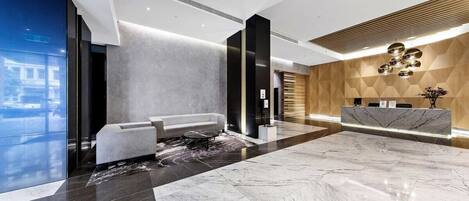 A modern lobby with a reception desk, seating area, and a large marble floor.
