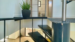 A modern staircase with metal railings and a potted plant.
