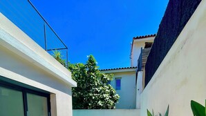 A modern outdoor pool area with a wooden deck, lounge chairs, and a glass-enclosed patio.