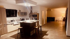 A modern kitchen with a central island, bar stools, and a dining table set for four.