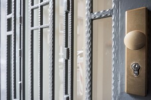 A close-up of a door with a textured metal grille and a brass doorbell with a round button.