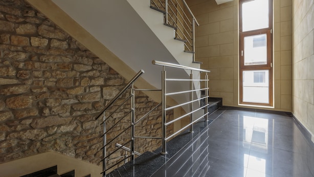A modern staircase with a stone wall on one side and a large window on the other.
