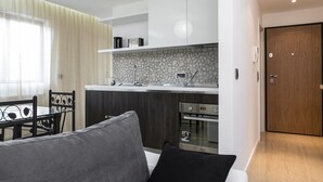 A modern kitchen with white cabinets, a stone backsplash, and a built-in oven.