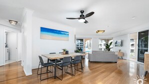 A spacious living area with a dining table, grey sofa, and a ceiling fan. - The Moroccan - 3 Bedroom Beachside Unit - Q Stay (Surfers Paradise)