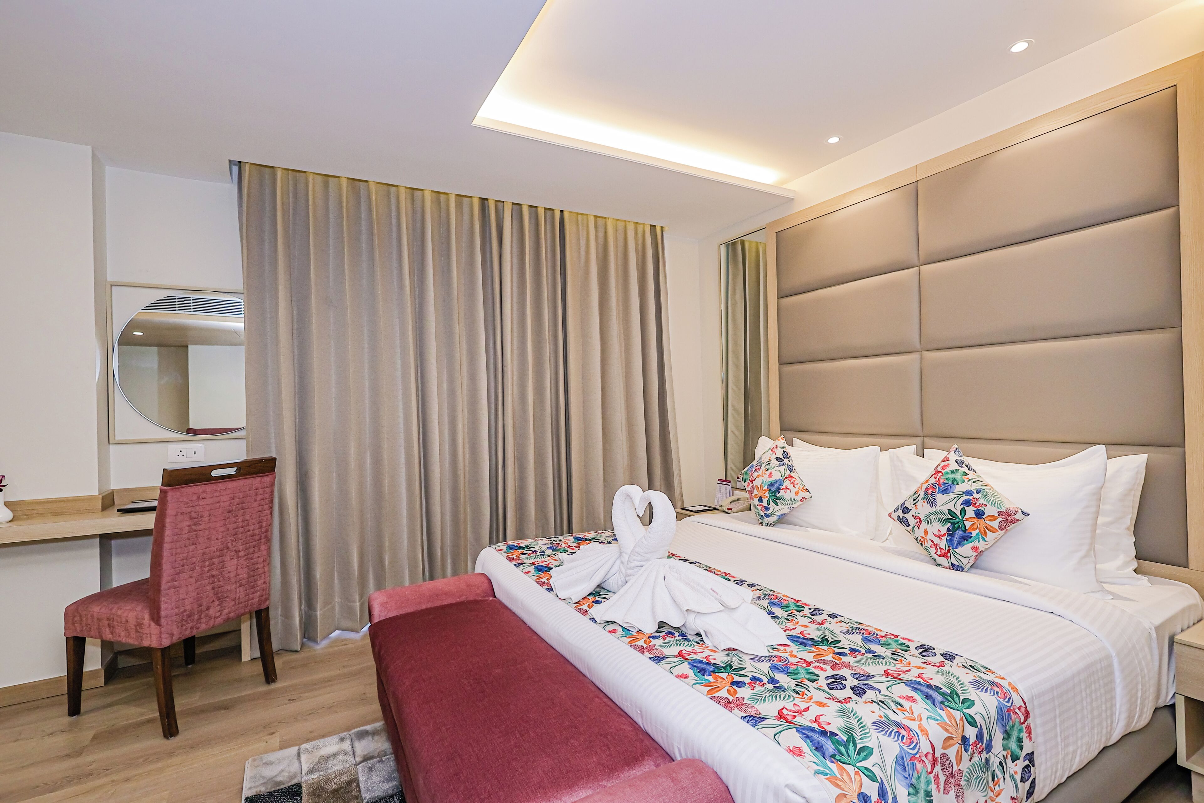 A hotel room with a bed, a desk, a chair, and a large window with curtains.
