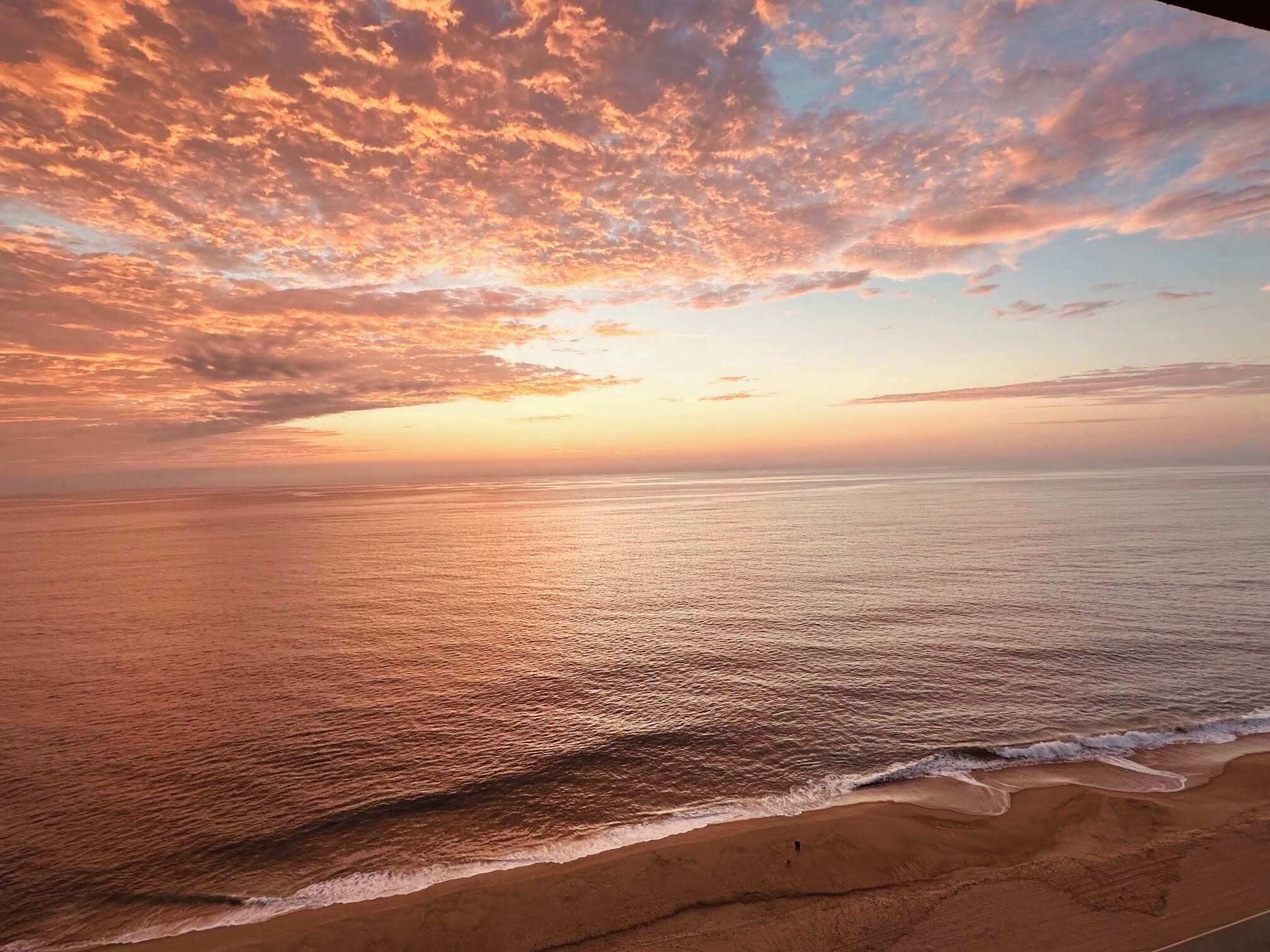 Ein Strand bei Sonnenuntergang mit Blick aufs Meer.