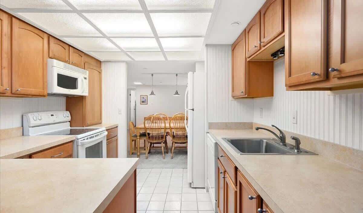 A compact kitchen with wooden cabinets, a microwave, stove, and a sink.