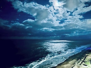 Un paysage côtier avec une plage et l’océan, sous un ciel nuageux.