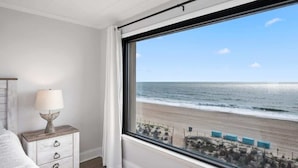 Ein Schlafzimmer mit einem großen Fenster mit Blick auf einen Strand.