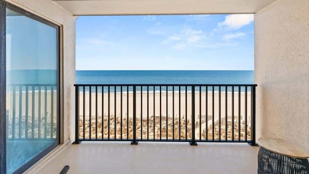 Ein Balkon mit Blick auf Strand und Meer.