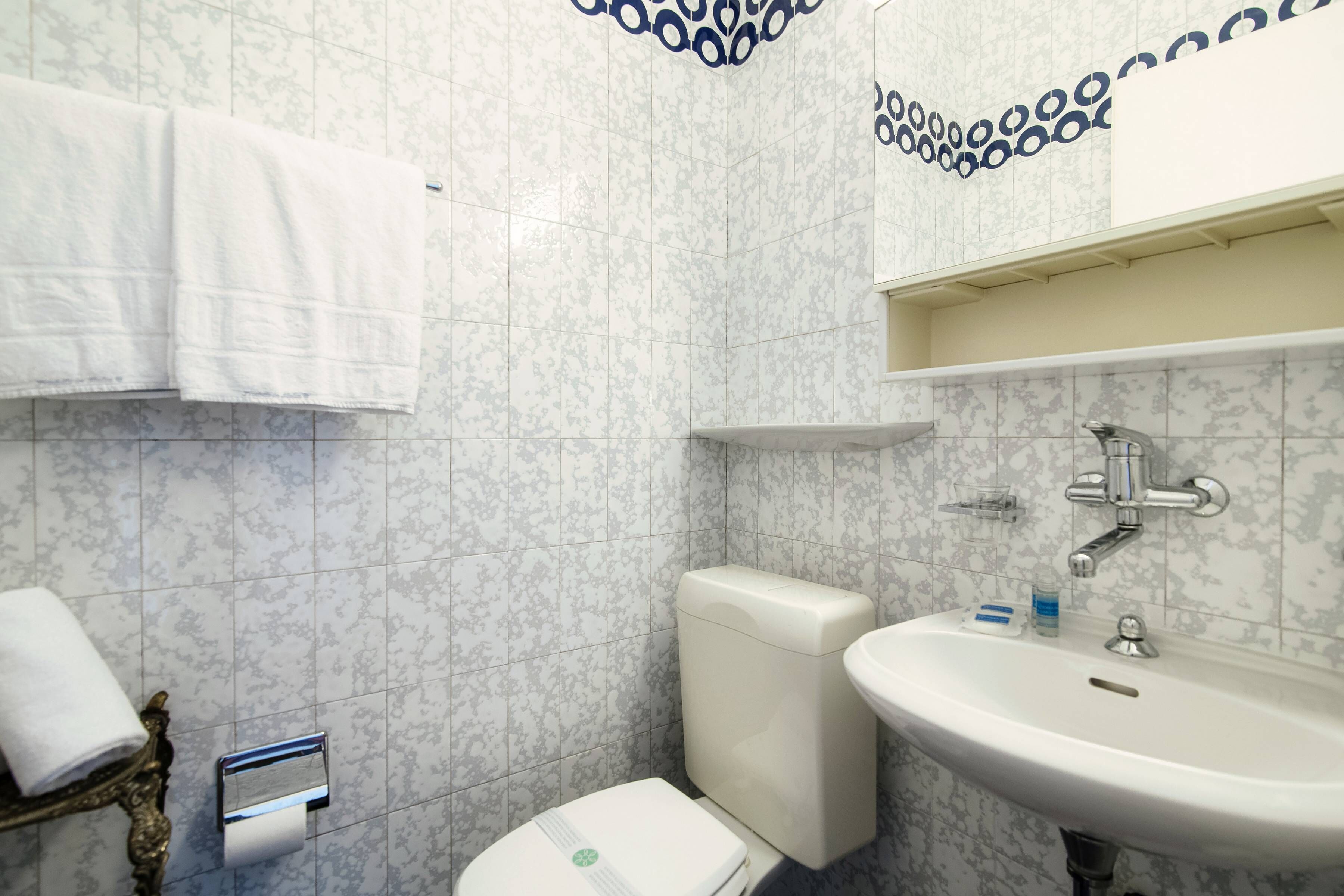 A bathroom with a toilet, sink, and decorative wall tiles.