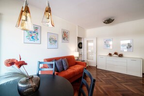Una sala de estar moderna con sofá, mesa de comedor y obras de arte en las paredes.