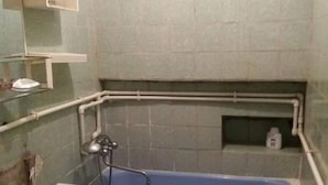 Een compacte badkamer met een wasmachine, een bad en een plank met toiletartikelen.