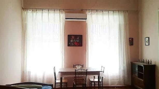 Een eetgedeelte met een tafel, stoelen, een schilderij aan de wand en een kast.