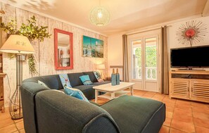 Un salon comprenant un canapé, une table basse, un téléviseur et un miroir décoratif.