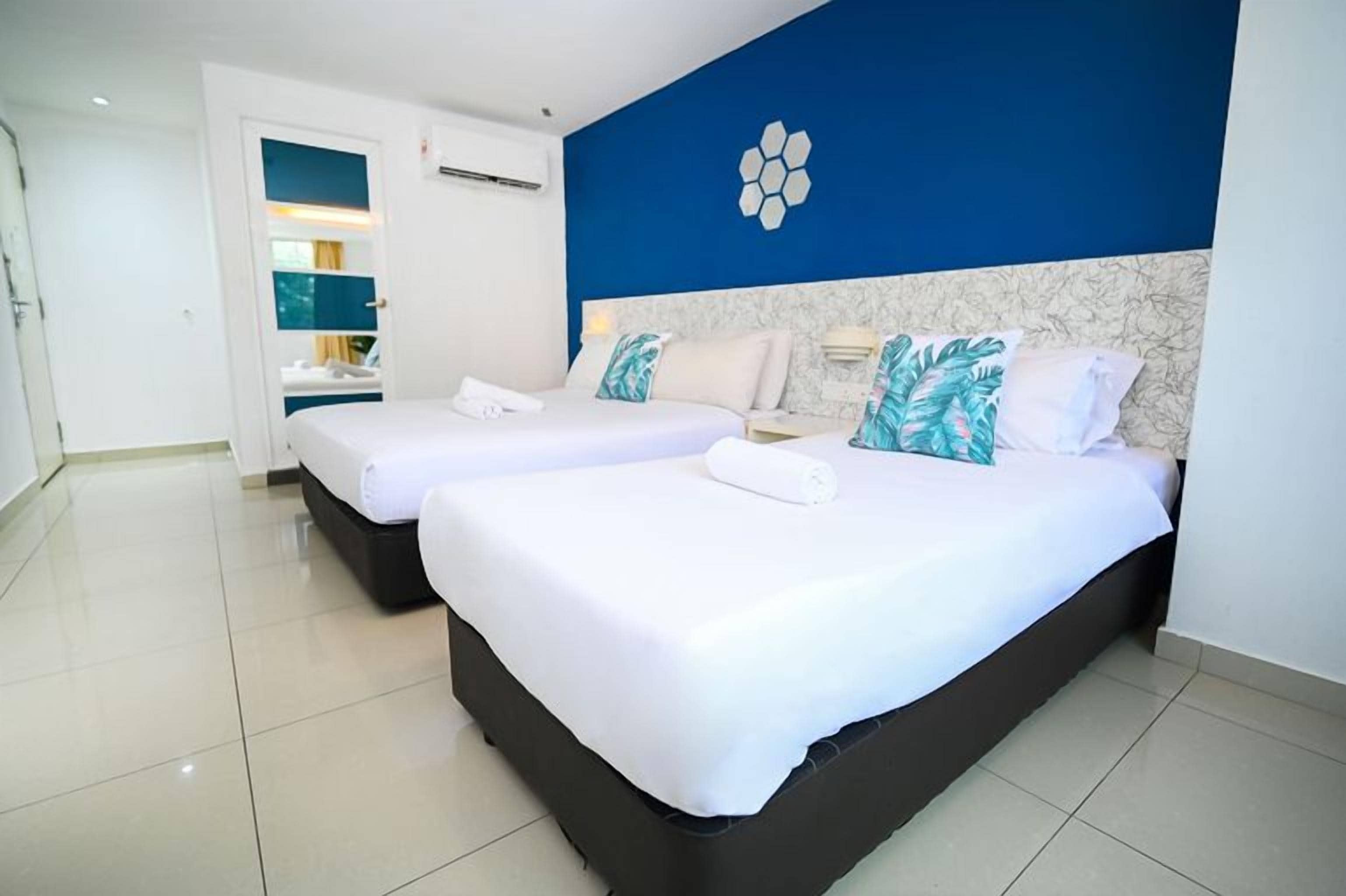 A hotel room with two beds, a blue accent wall, and a modern design.