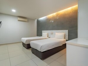Habitación de hotel con dos camas, un espejo grande y una lámpara moderna.
