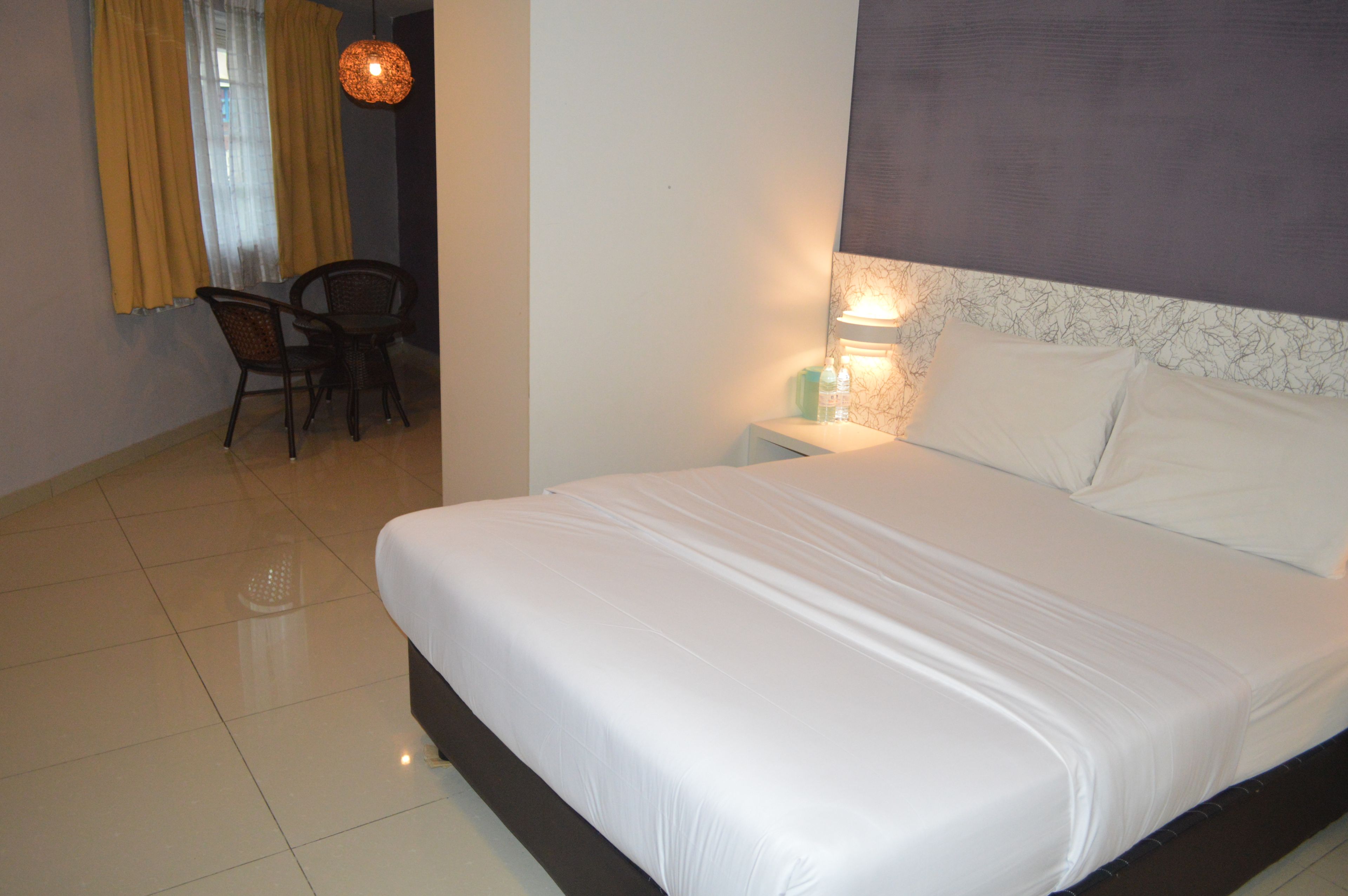 Une chambre d’hôtel avec un grand lit, une chaise, une table et une table de chevet avec une lampe.
