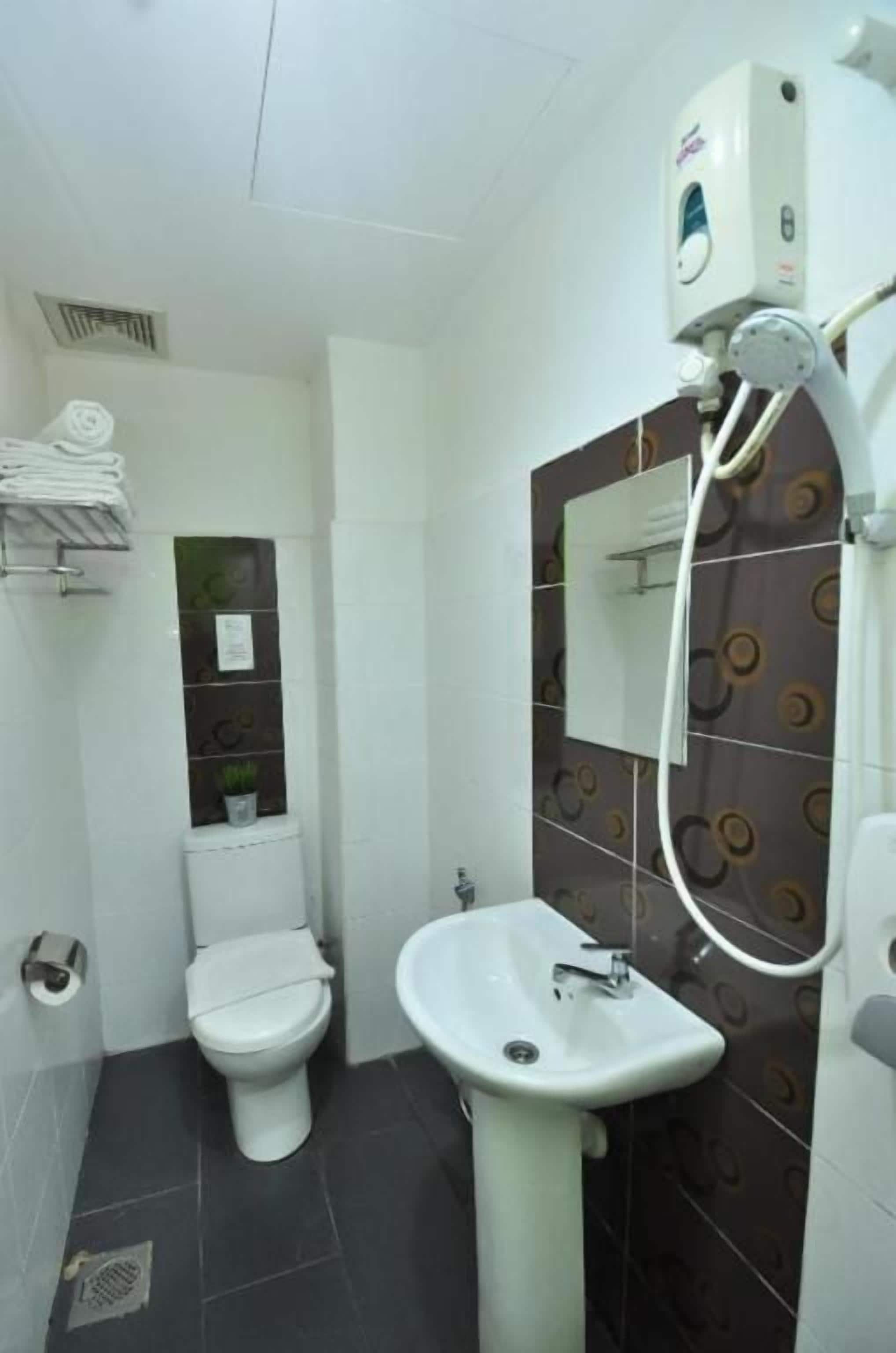 A bathroom with a toilet, sink, and a mirror.