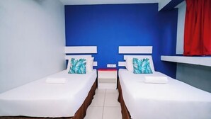 Une chambre double avec deux lits, du linge de lit blanc et des murs bleus.