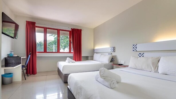 A hotel room with two beds, a desk, a chair, and a TV mounted on the wall. - Swing & Pillows @ PJ SS2 (Petaling Jaya)