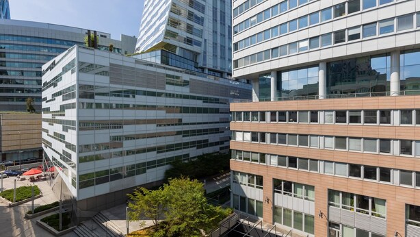 A modern building with a glass facade, multiple floors, and a mix of rectangular and square windows.