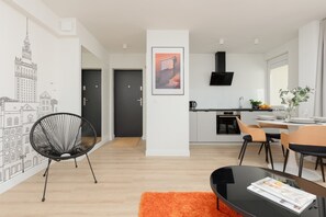 A modern apartment with a dining area, kitchen, and a large window.