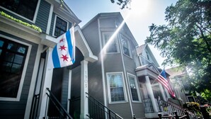 Une maison à deux étages avec un porche et un drapeau.