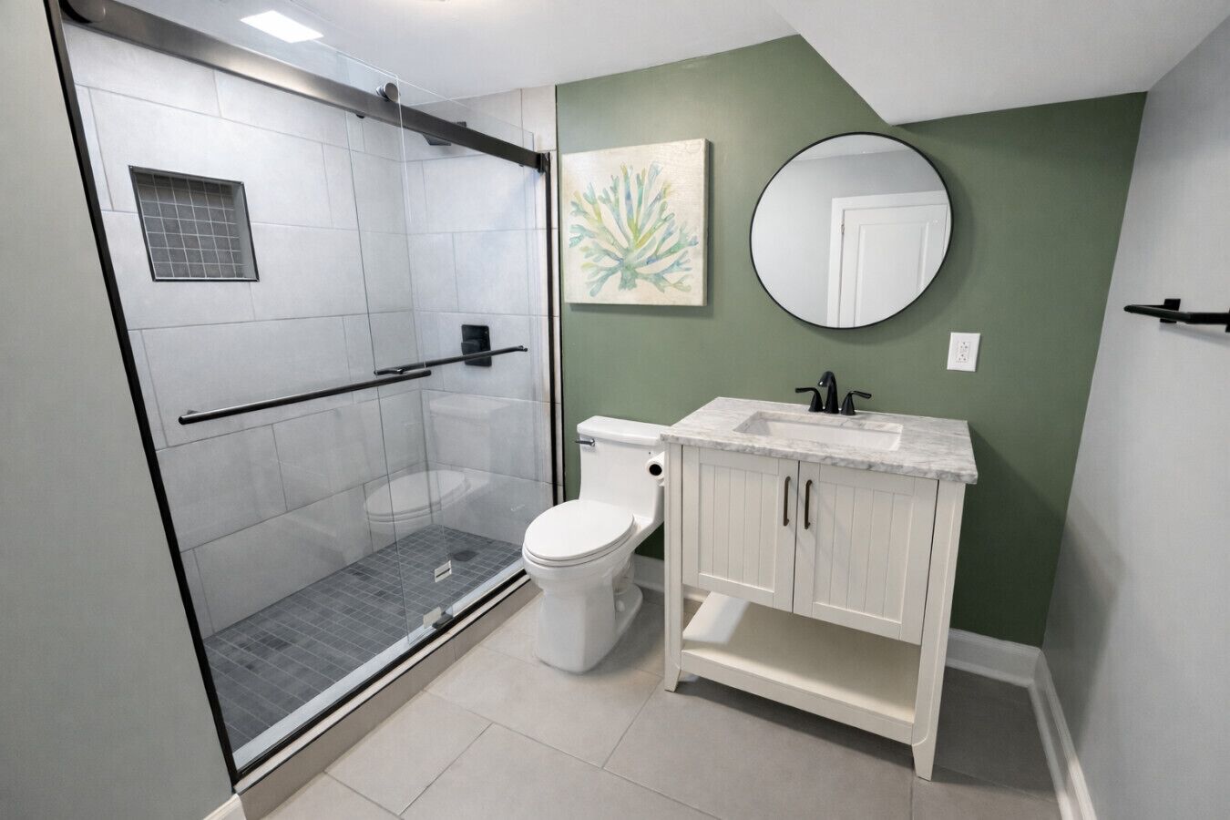 A bathroom with a glass-enclosed shower, white toilet, and vanity with a sink.