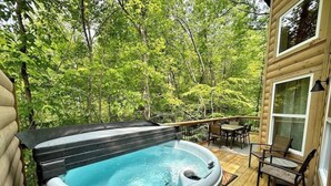 A hot tub on a wooden deck surrounded by trees.