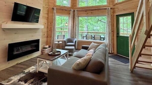 A cozy cabin interior with a fireplace, a sofa, and a television.