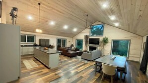 Ein modernes Interieur mit Küche, Essbereich und Wohnzimmer, mit Holzböden und einer geneigten Decke.