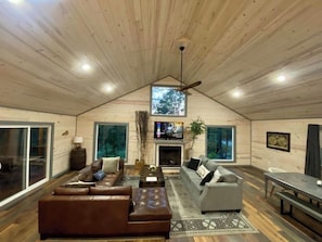 A spacious loft with a high ceiling, large windows, a fireplace, and a dining area.