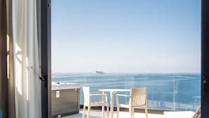 Varanda com vista para o mar, uma cama e duas cadeiras.
