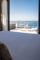 Un balcón con vista al mar, una cama y dos sillas.