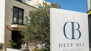 Placa do Deep Blu Boutique Hotel, com estilo arquitetônico moderno, área de estar ao ar livre e vista para a entrada do edifício.