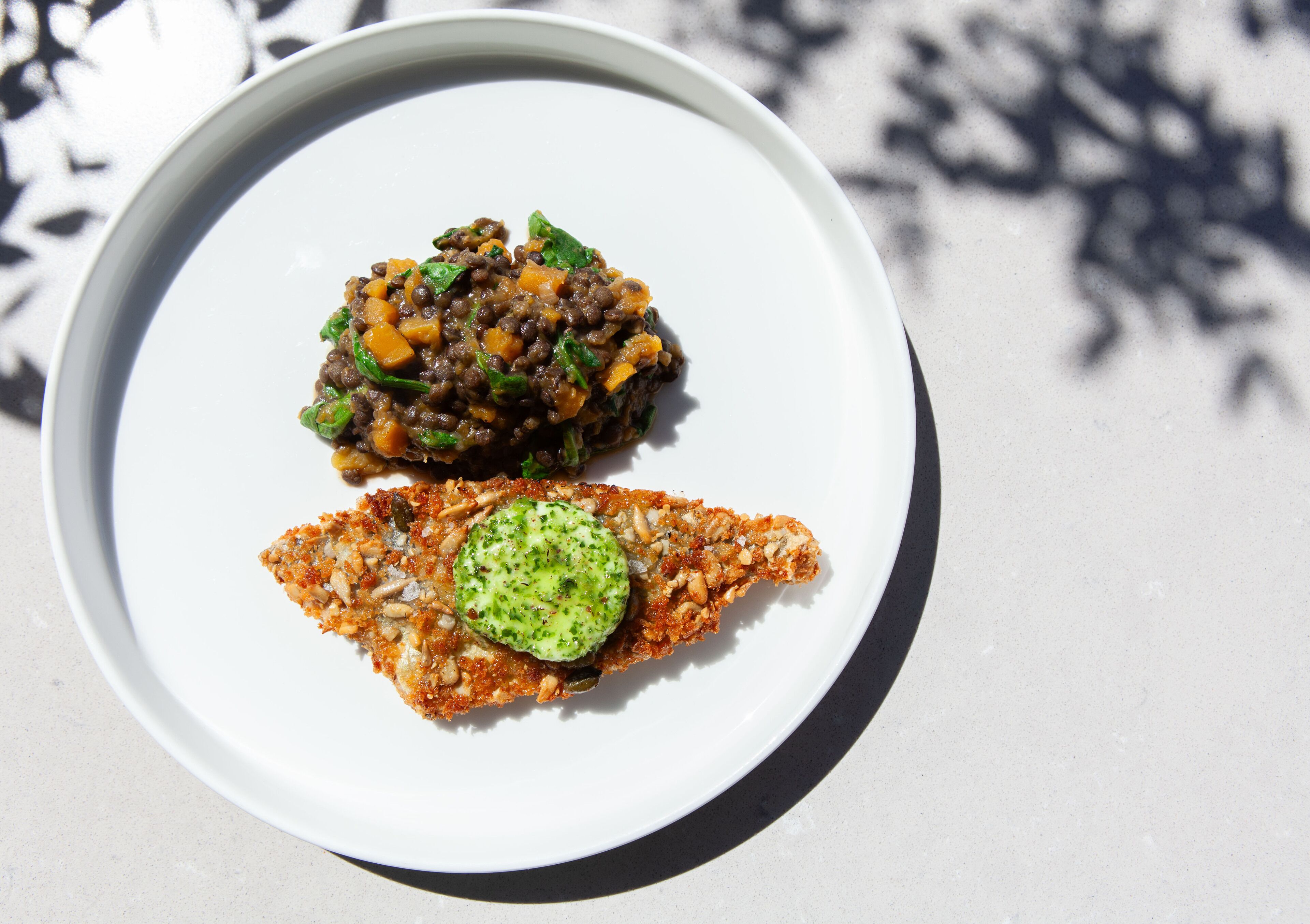 A white plate with two dishes: a meat-based dish and a vegetable-based dish.