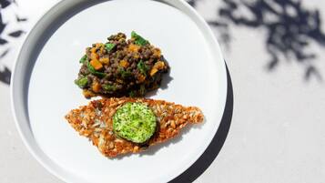 A white plate with two dishes: a meat-based dish and a vegetable-based dish.