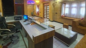 Un hall d’hôtel moderne avec un comptoir d’accueil, un espace salon et une grande fenêtre agrémentée de rideaux.
