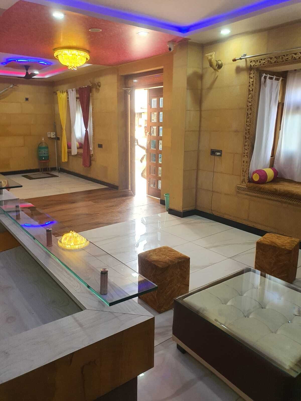 A modern lobby with a glass reception desk, a tufted sofa, and a chandelier.