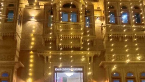 Un imposant bâtiment doté d’une entrée centrale, de balcons richement décorés et d’une série de marches menant à l’entrée.