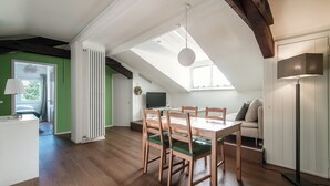 A dining area with a wooden table and chairs, a white radiator, and a ceiling fan. - Mansarda Verde (Tresa)