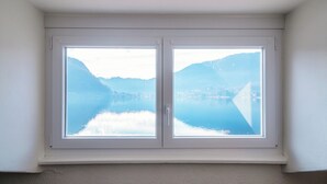 A window with a view of a calm lake and mountains. - Mansarda Verde (Tresa)