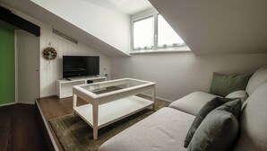 A modern living room with a glass-top coffee table, a flat-screen TV, and a green door. - Mansarda Verde (Tresa)