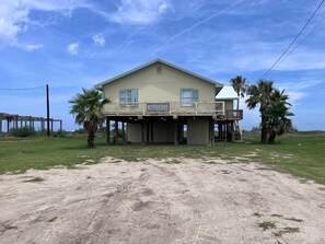 A two-story house with a balcony, a sign reading "Beach House," and a sandy ground in front. - Faye DoDo - Beachfront - Island Realty (Grand Isle)