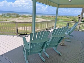 A covered deck with Adirondack chairs and a view of the beach. - Faye DoDo - Beachfront - Island Realty (Grand Isle)