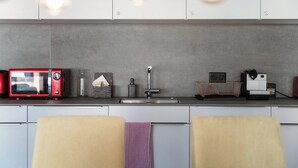 Een moderne keuken met een roestvrijstalen spoelbak, een rode magnetron en een koffieapparaat.