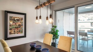 Een eetgedeelte met een houten tafel, drie blauwe kommen en een ingelijste poster aan de muur.