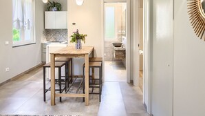 Une cuisine moderne avec une table en bois et des tabourets de bar, une plante en pot et un luminaire suspendu.